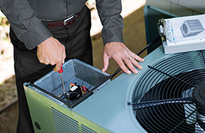 Service tech repairing AC unit