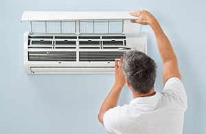 Man adjusting a ductless AC unit