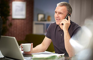 Man on phone holding cup of coffee 