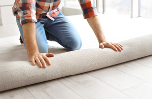 Person rolling carpet out in room