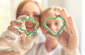 Mother and daughter holding up cookie cutters